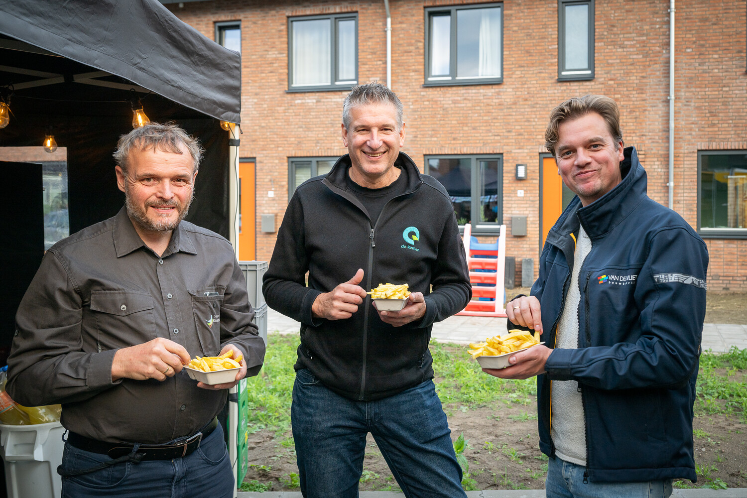 3 personen staan een frietje te eten.