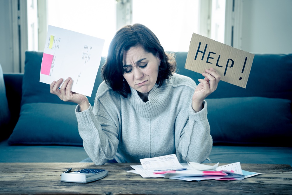 Mevrouw aan tafel met administratie voor haar. Ze houdt bordje 'help' omhoog