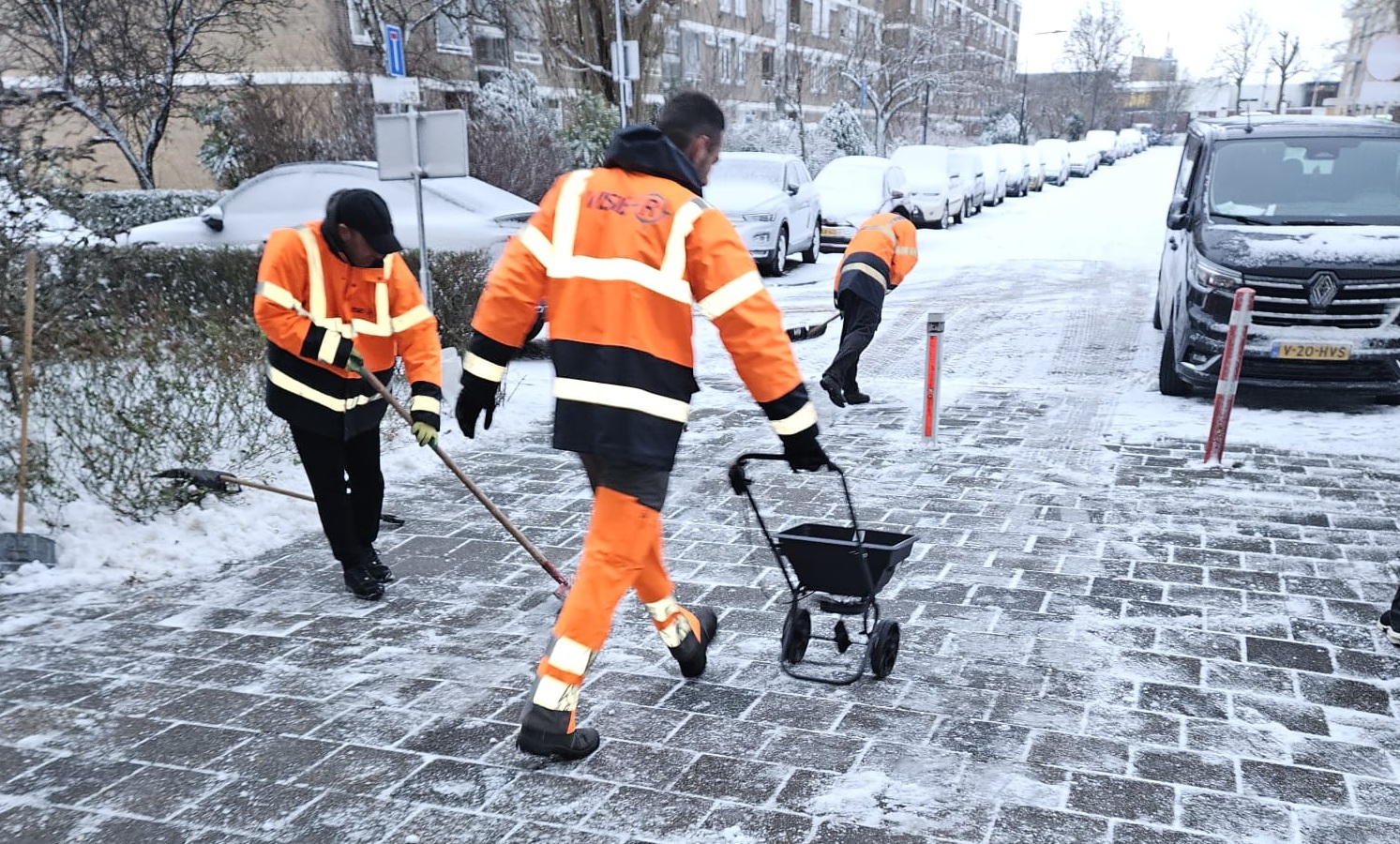 Mensen die de stoep sneeuwvrij maken met scheppen en strooizout