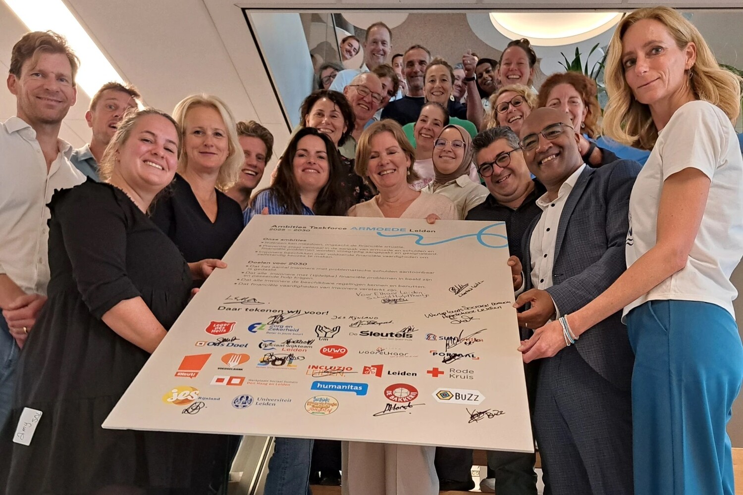 Personen die samenwerken aan armoede rondom een bord met handtekeningen