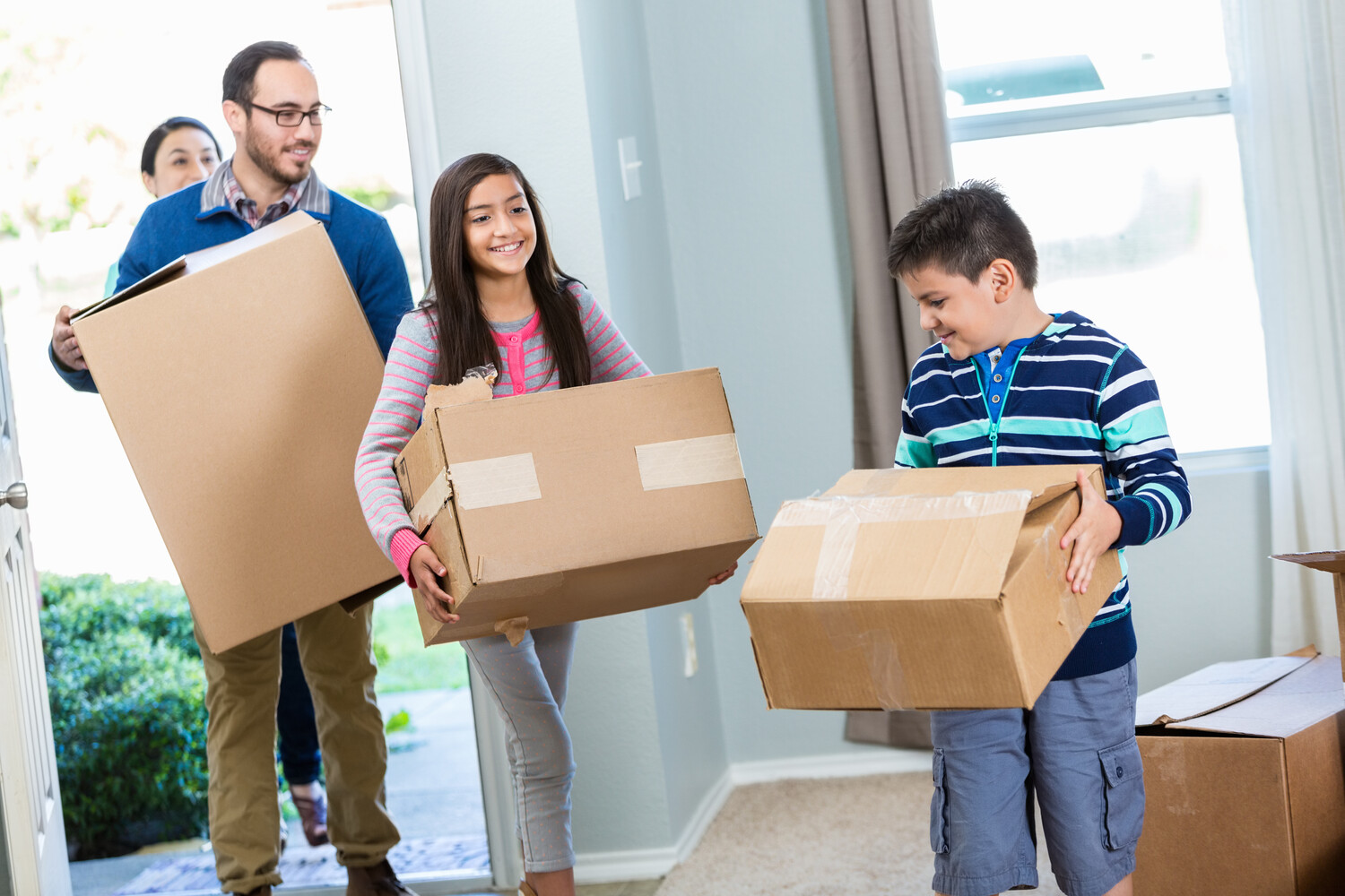 Gezin loopt woning binnen met verhuisdozen