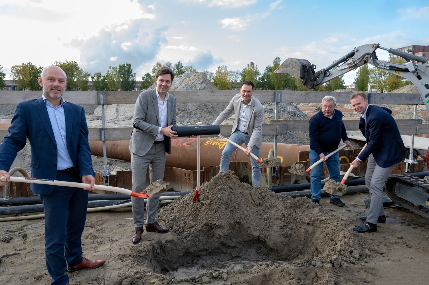 Samenwerkende partijen en Julius Terpstra begraven tijdcapsule bij de start bouw