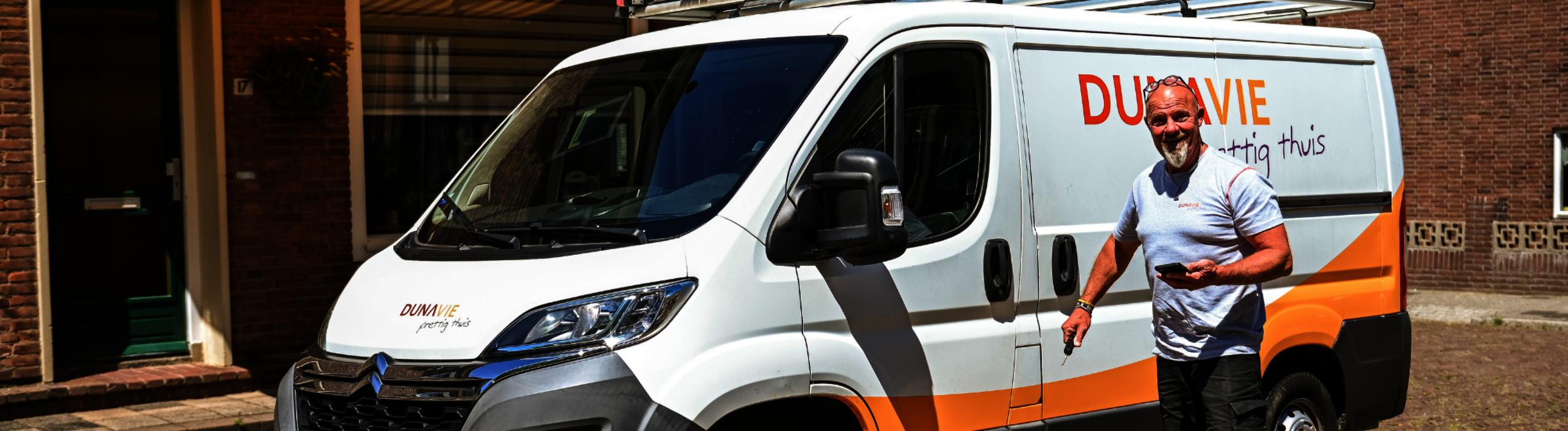 Banner: vakman van Dunavie staat naast zijn werkbus