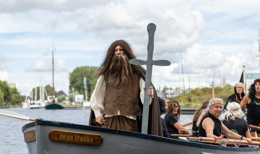 Persoon in historische kleding staat op een boot