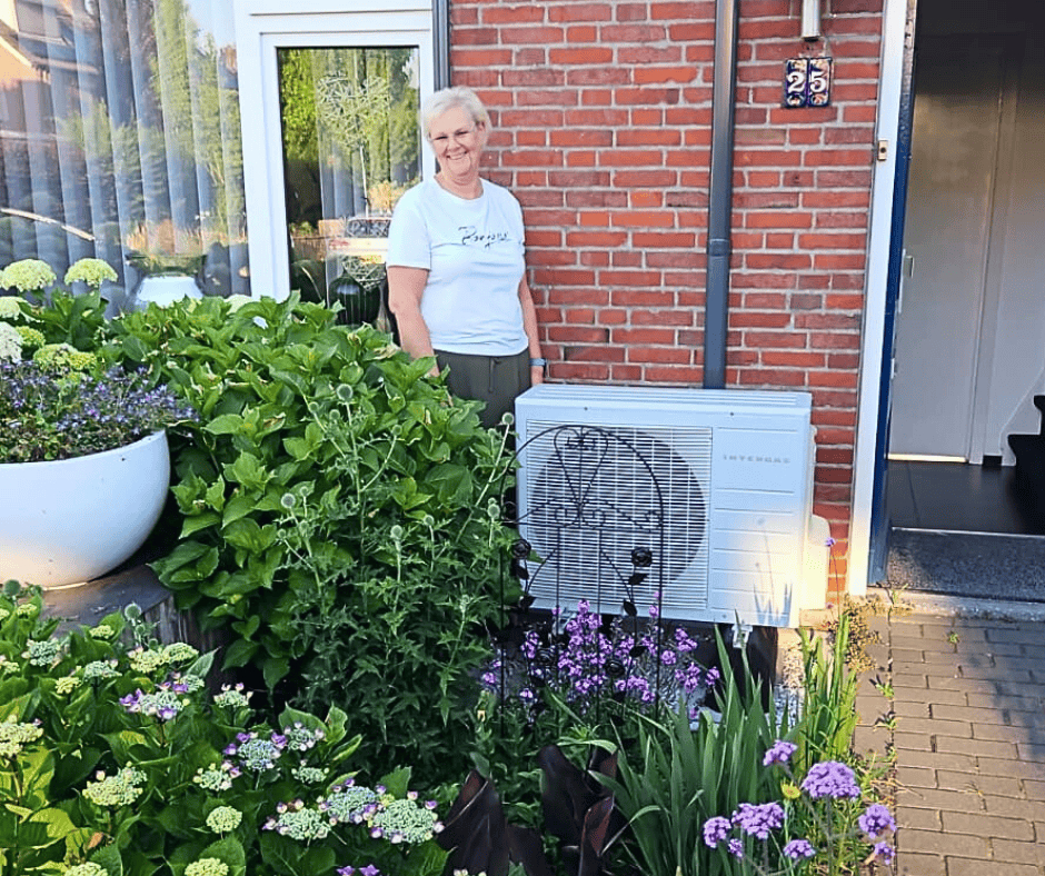 Anne-Marie in haar voortuin naast de buitenunit van de hybride warmtepomp