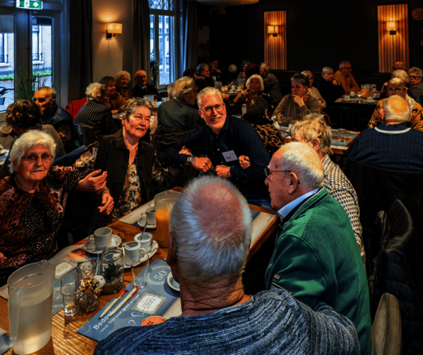 Tafel met daaromheen huurders die de armen in elkaar gehaakt hebben lachen en bewegen op de muziek