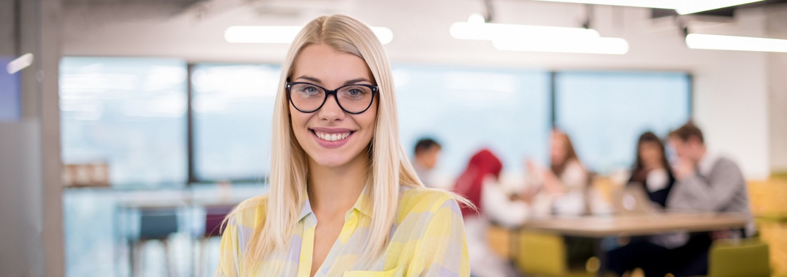 Jonge medewerker met op achtergrond collega's - vacatures en stage Goed Wonen Gemert