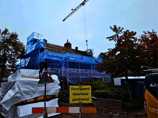 Overzichtfoto plaatsing biobased dakplaten. Rijtje huizen op achtergrond. Op voorgrond stapel dakplaten.