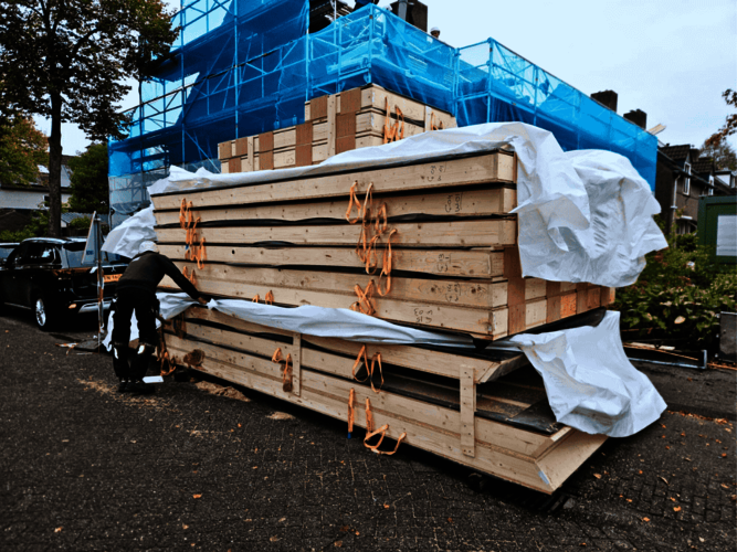 Stapel houten biobased dakplaten met iemand erbij die het plastic om de stapel verwijderd.