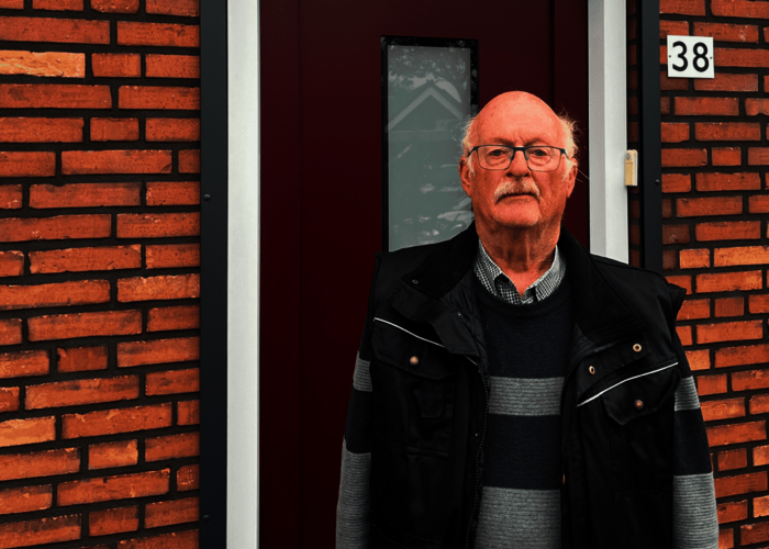 Arie Manders staand voor de voordeur van zijn woning