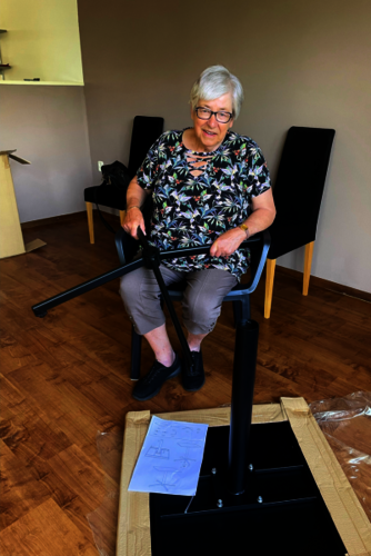 Mien Martens (oudere huurder) zittend in een stoel een tafel in elkaar aan het zetten.