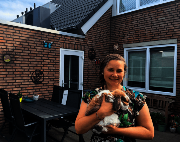 Wiesje in haar achtertuin met in haar armen één van haar konijnen