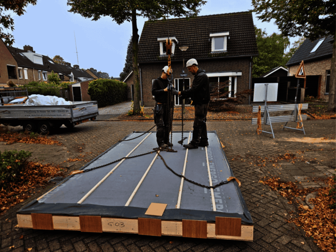 2 medewerkers bevestigen de biobased dakplaat met kettingen aan de hijskraan.