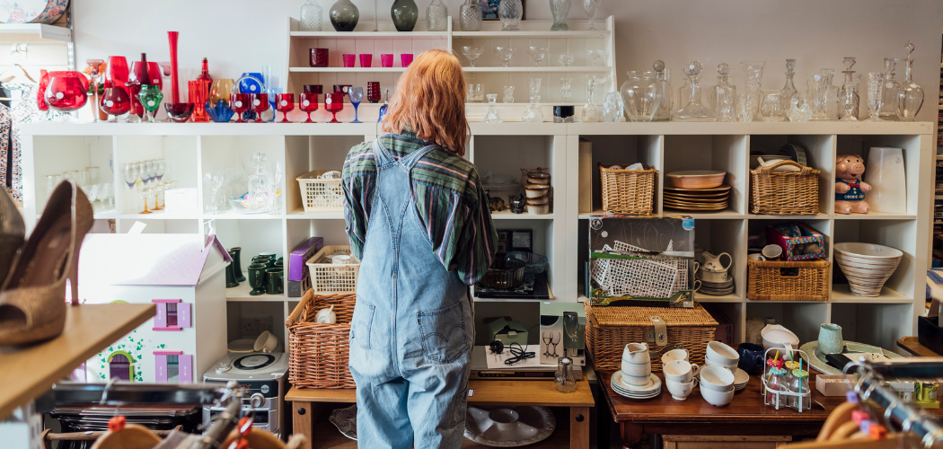 Foto van een hoekje in een kringloopwinkel waar een persoon loopt rond te snuffelen