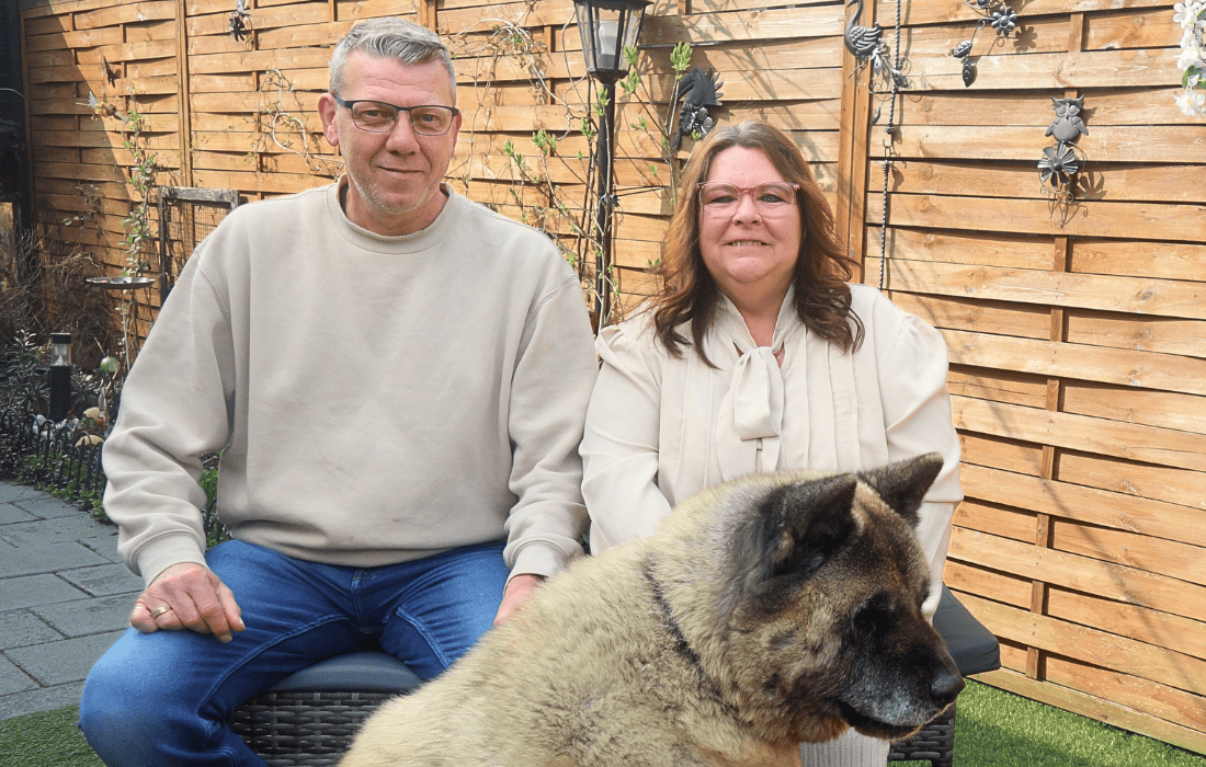 Dimi en Bianca met hun hond zittend op een bankje in hun achtertuin