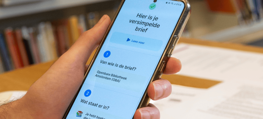 Foto van een GSM in een hand met daarop zichtbaar de tekst 'Hier is je versimpelde brief'