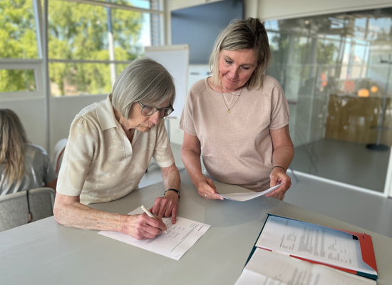 Nellie en wooncoach Mascha aan een statafel. Nellie tekent het huurcontract