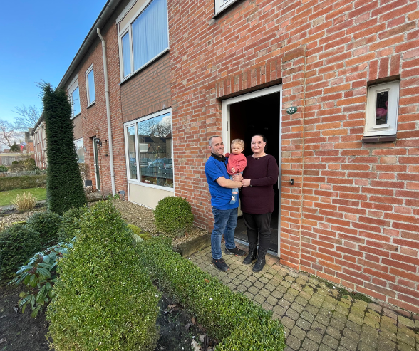 Rijtje woningen met in de voordeur van hun woning het gezinnetje.