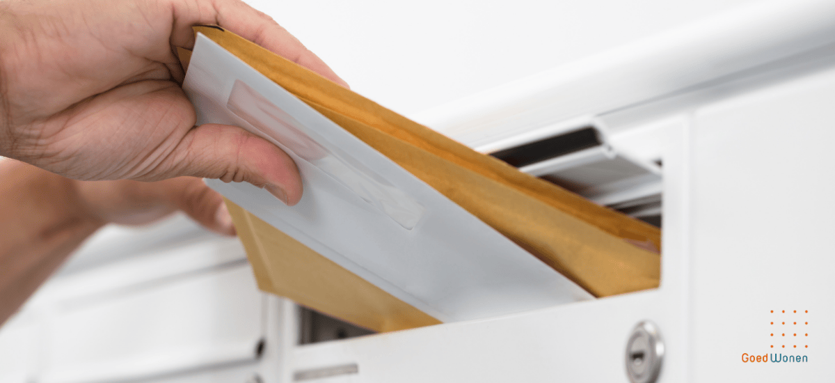 Hand die een witte en twee bruine enveloppen in een witte brievenbus stopt
