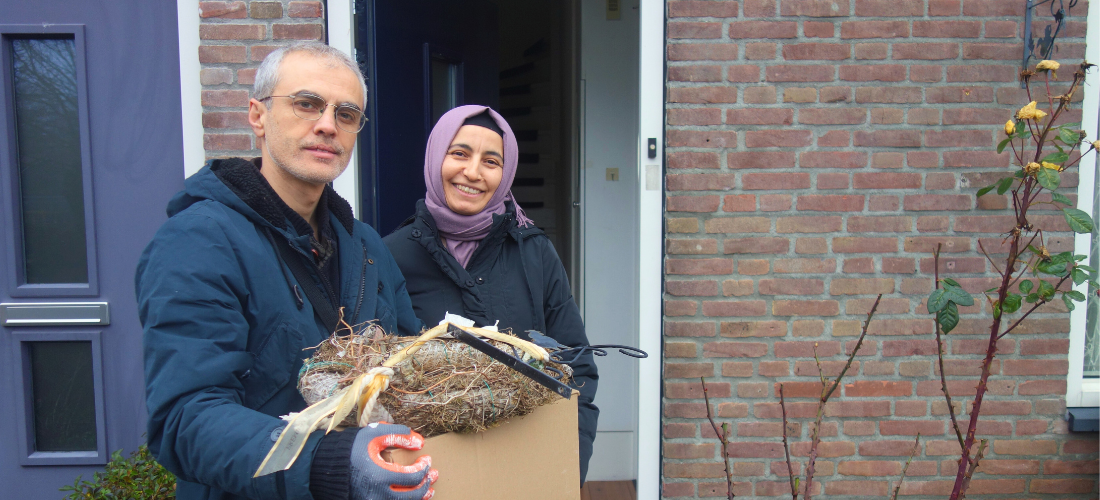 Hüdaverdi en Safinaz Taskin met een verhuisdoos in de handen voor de geopende deur van hun nieuwe woning