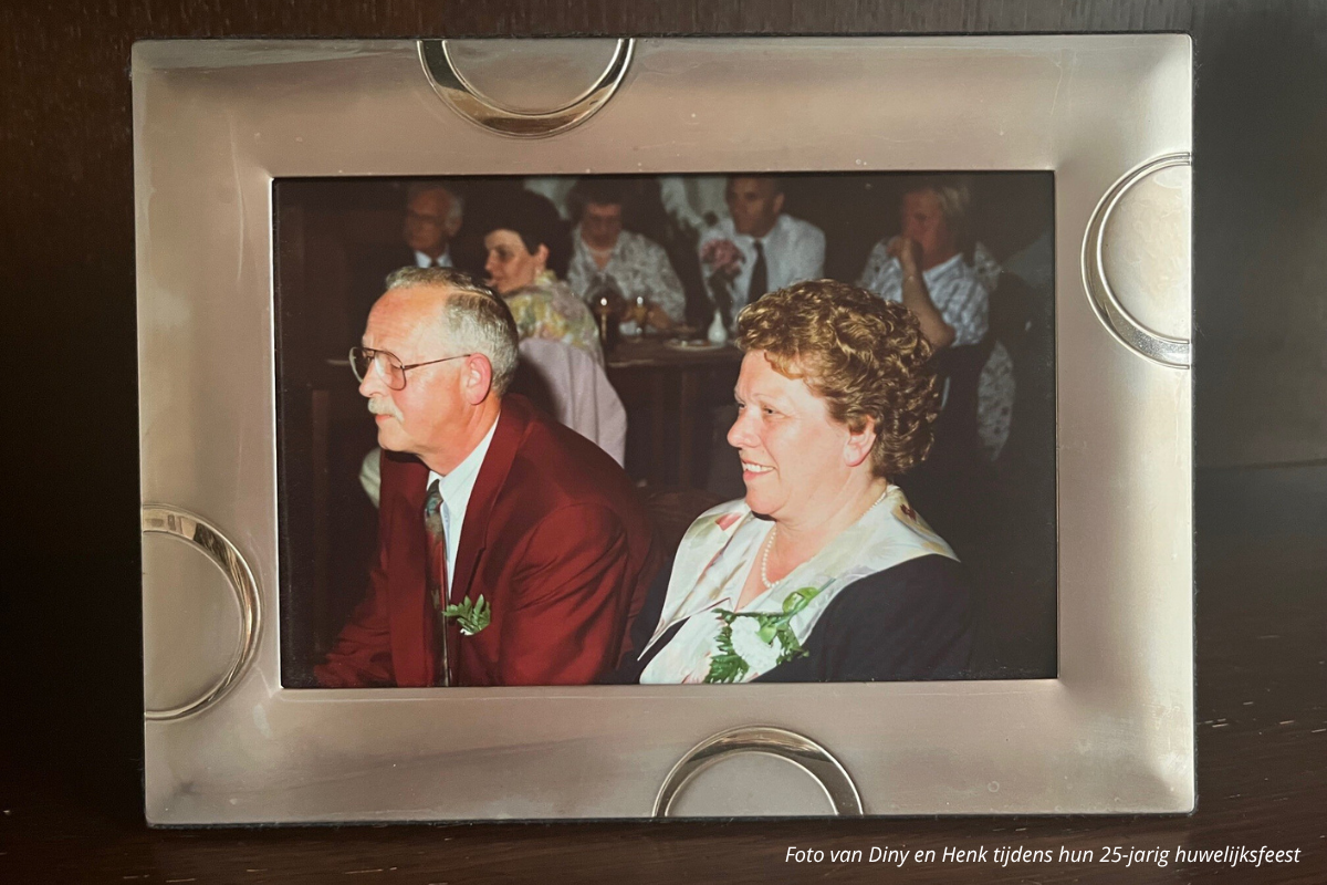 Foto van Diny en Henk tijdens hun 25-jarig huwerlijksfeest. Zittend op een stoel. 