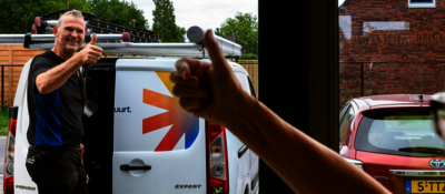 Huurder steekt duim op naar vakman die buiten bij zijn bus staat en een duim naar haar opsteekt.