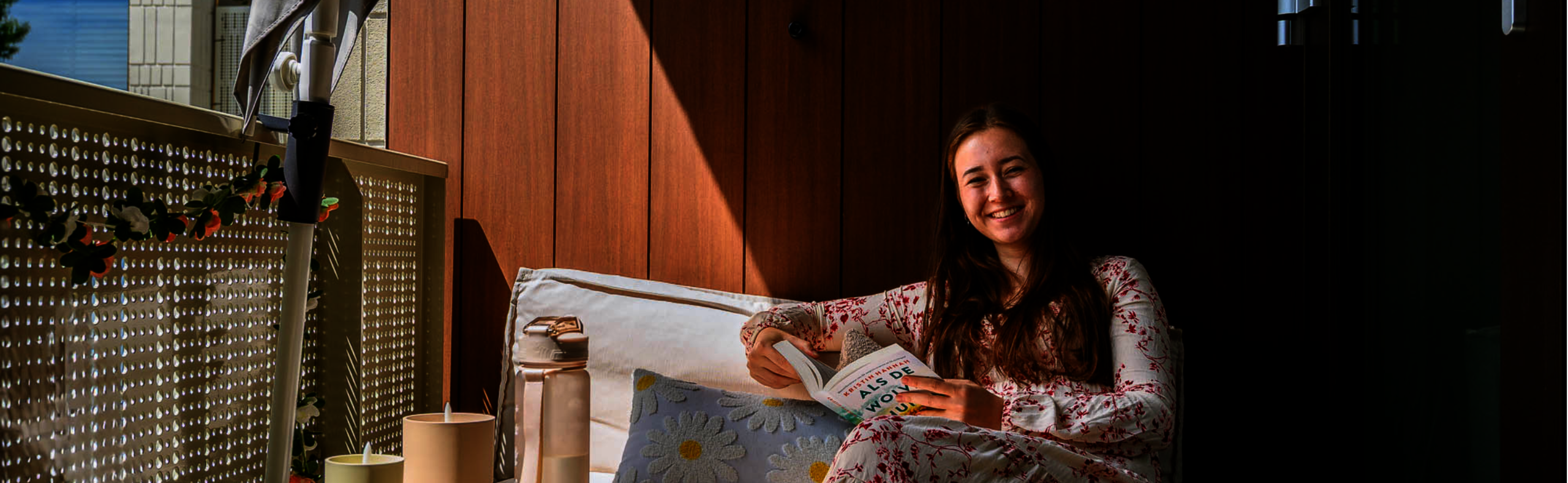 Jonge huurder op haar balkon kijkt op van haar boek