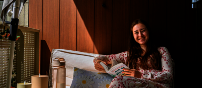 Jonge huurder op haar balkon kijkt op van haar boek