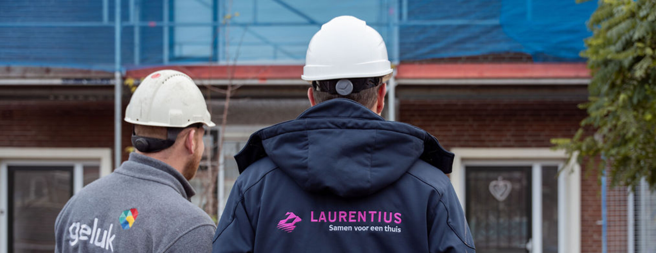 Twee bouwvakkers voor een woning die in de steigers staat