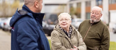 Drie oudere mensen met elkaar in gesprek op straat