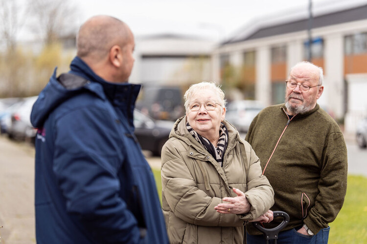 Drie oudere mensen met elkaar in gesprek op straat