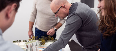 Groepje mensen bekijkt een maquette van een buurt