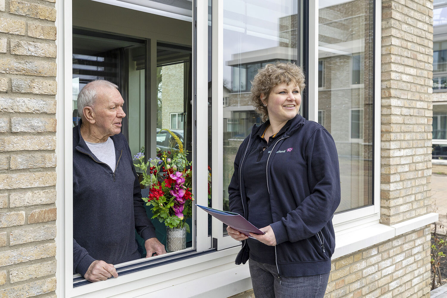 Wijkconsulent praat door raam met bewoner