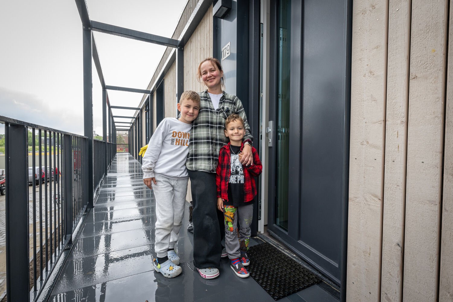 Op het beeld is Irina met haar twee kinderen voor haar voordeur te zien.