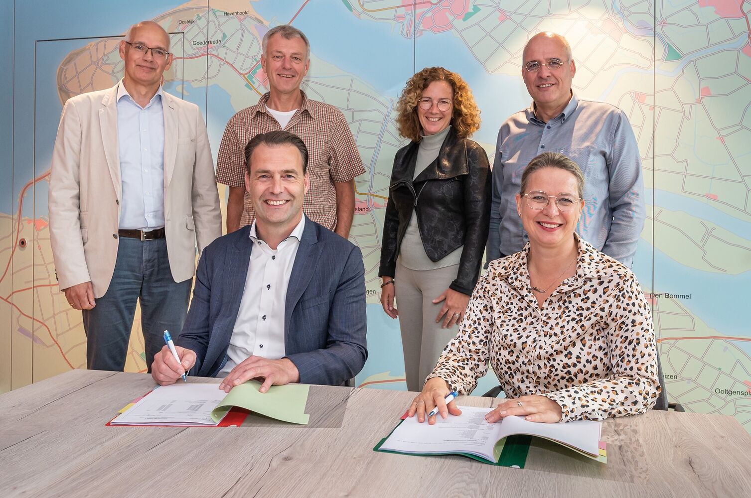 Op het beeld zijn staand van links naar rechts te zien: René Kom (Kroon & De Koning), Andre Smits, Petra van der Waal-Kom en Kees van Dam (allen Oost West Wonen). Ondertekenaars: Ivo Zweekhorst (Kroon & De Koning) en Marleen van de Kamp (Oost West Wonen).