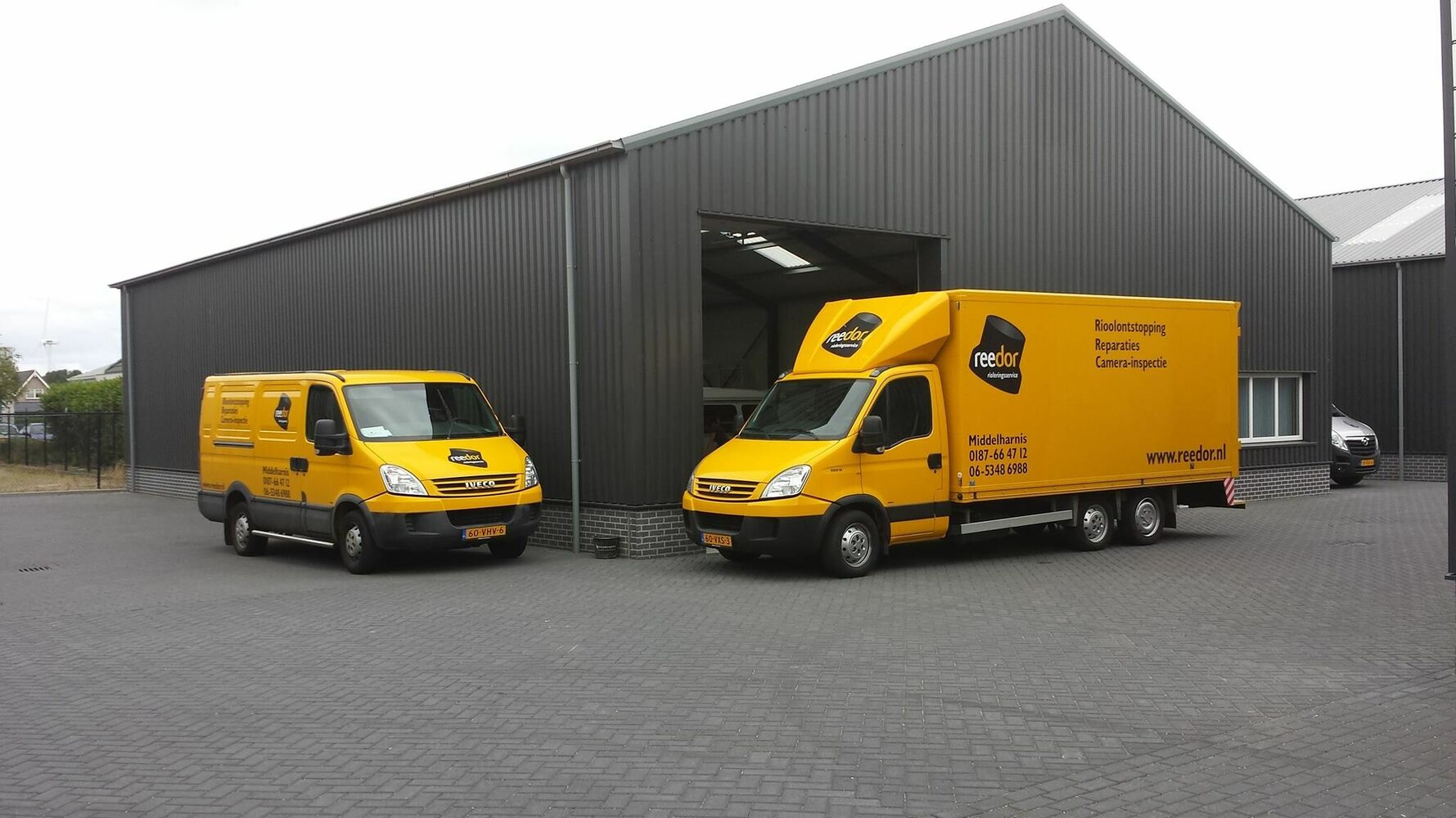 Op het beeld zijn de bedrijfsbussen van Reedor te zien voor een grote schuur/opslag.