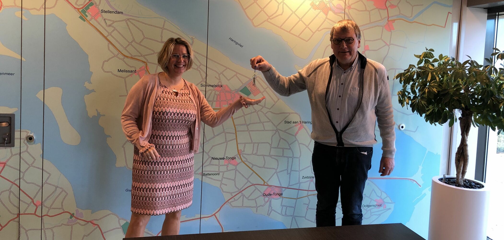 Op het beeld is te zien dat Marleen van de Kamp symbolisch de sleutel van Oost West Wonen overhandigd krijgt van Jan Salverda.
