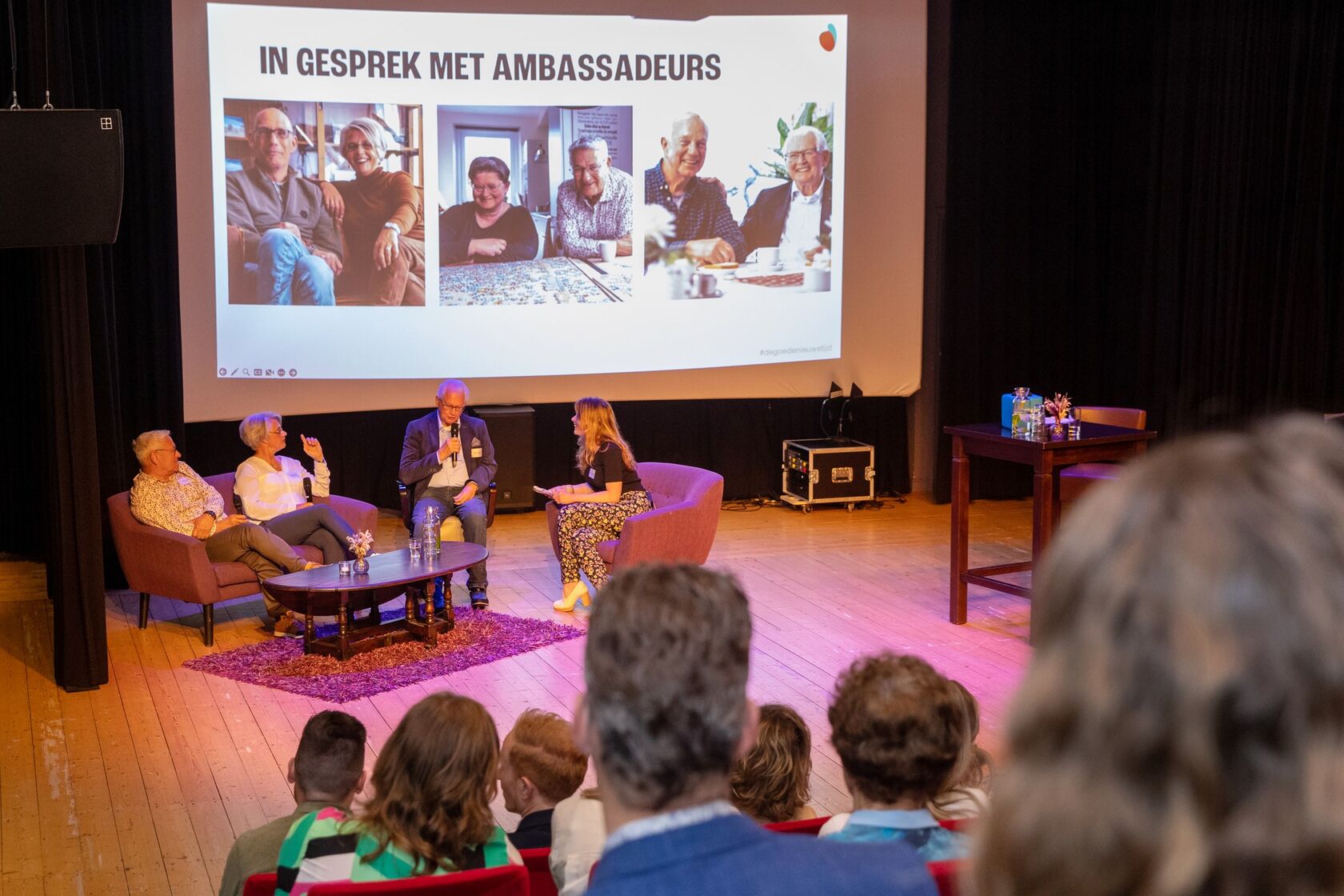 Een beeld van een bijeenkomst met een PowerPoint presentatie waarop staat "In gesprek met ambassadeurs".