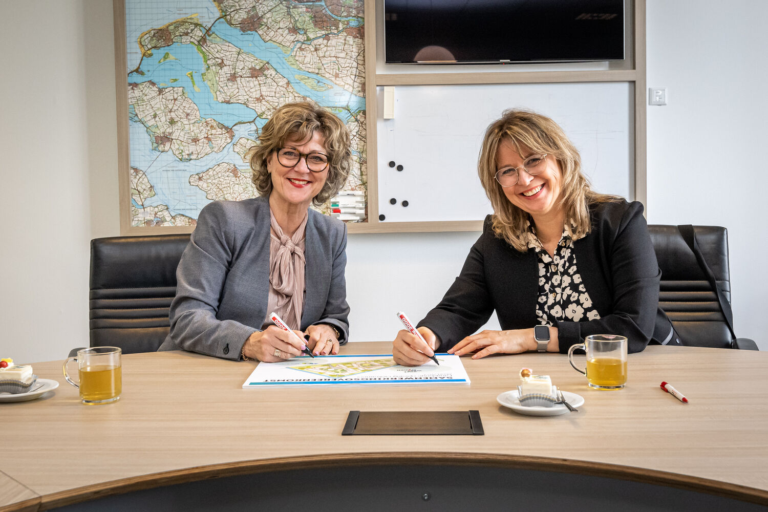 Een beeld waar de samenwerkingsovereenkomst wordt ondertekend door burgemeester Ada Grootenboer-Dubbelman en Marleen van de Kamp, directeur-bestuurder bij Oost West Wonen.