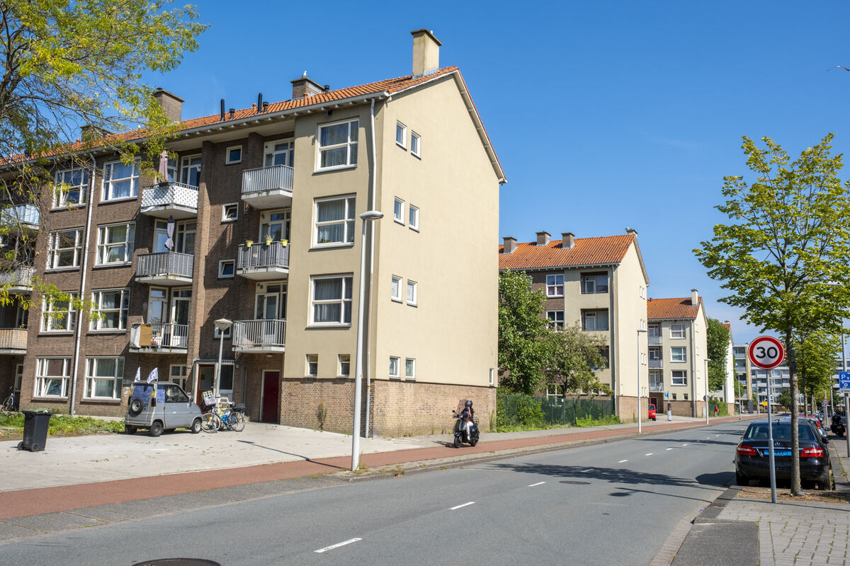 Foto van de 4 woongebouwen aan De Savornin Lohmanstraat. De gebouwen zijn lichtgeel en hebben een schuin rood dak. Er is 1 portiek per 8 woningen.