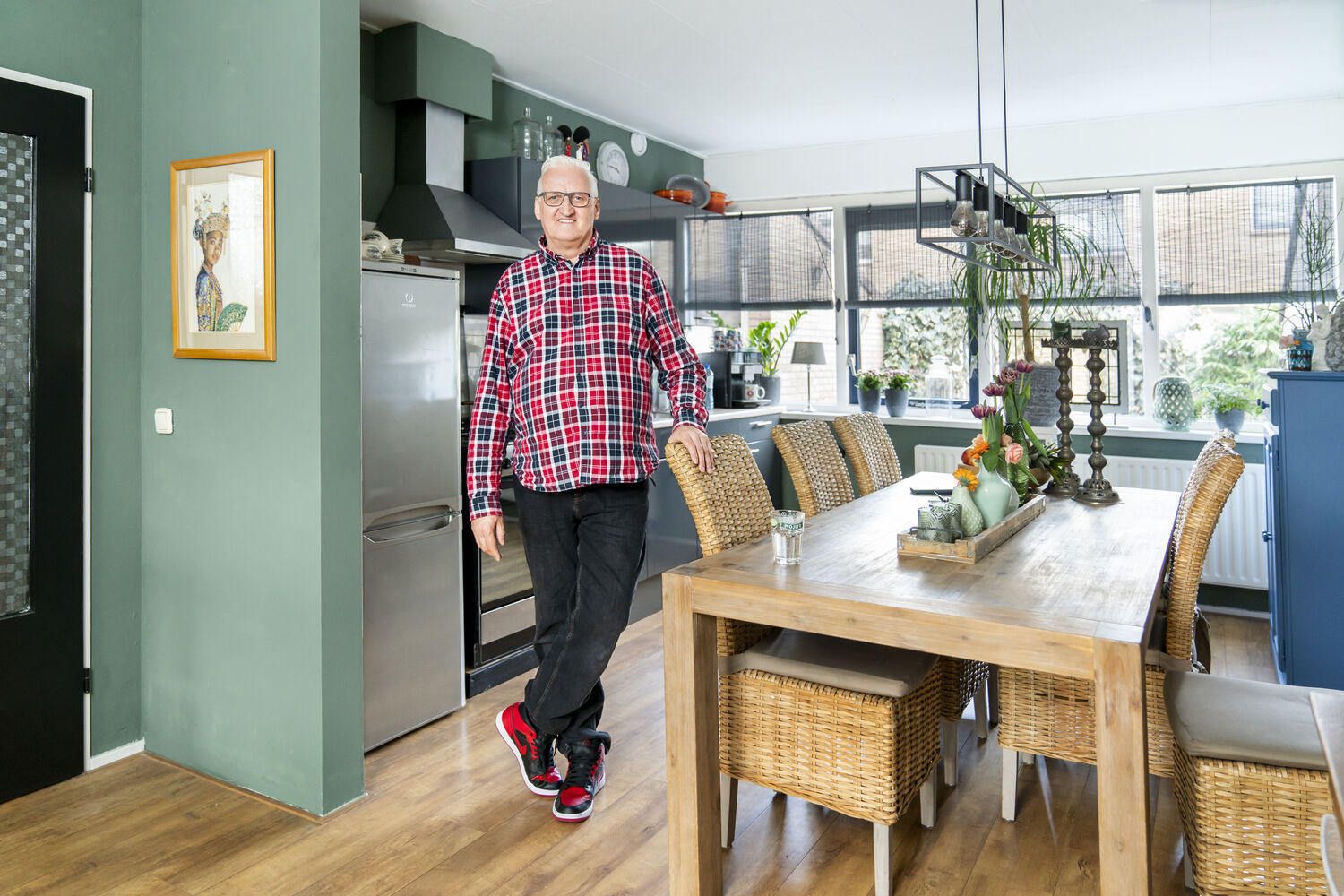 Persoon zit in keuken met laptop, tweede persoon tilt verhuisdoos