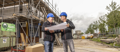 Collega's Thús Wonen op een bouwplaats met een bouwtekening