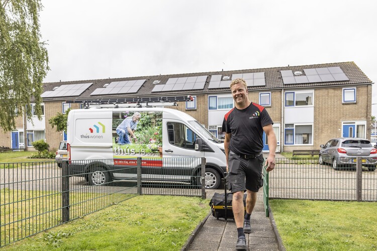 Vakman die naar een huurhuis loopt met Thús Wonen bus op de achtergrond