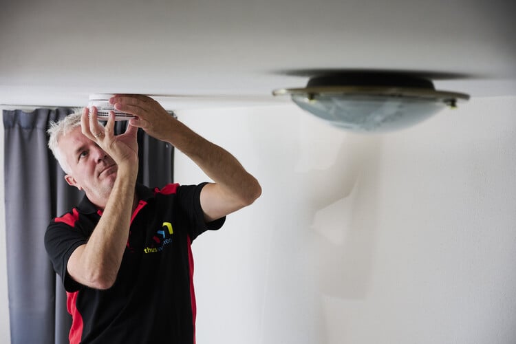 Vakman die een rookmelder aan het installeren is