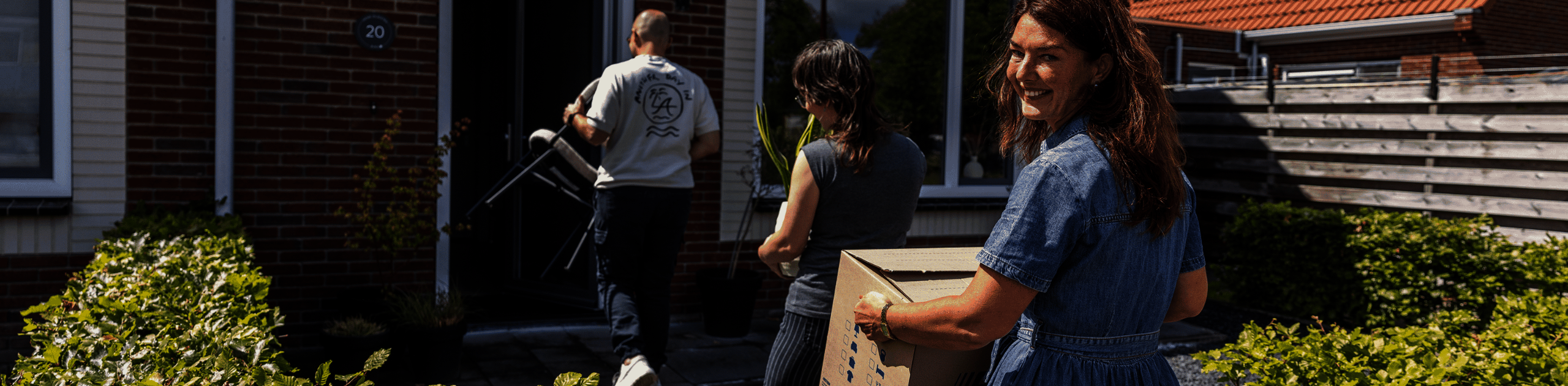 Vrouw met verhuisdoos die een huis in loopt