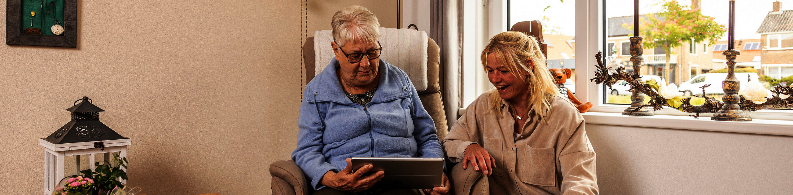 Oudere dame op tablet die wordt geholpen door vrouw