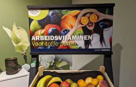 Afbeelding van een kistje met vers fruit en een poster erboven met de tekst: Arbeidsvitaminen, voor toffe peren.