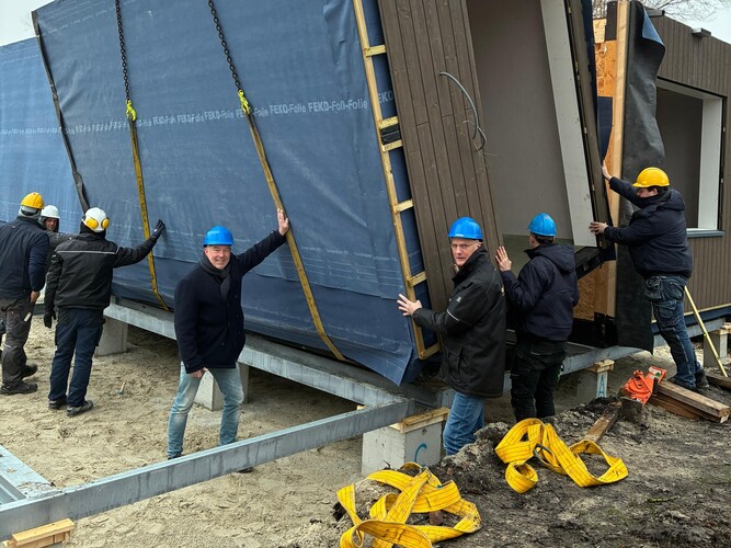 Wethouder Henk Zwiep van de gemeente Borger-Odoorn en projectleider Otto Lugers van Woonservice plaatsen samen met het bouwteam de eerste woning.