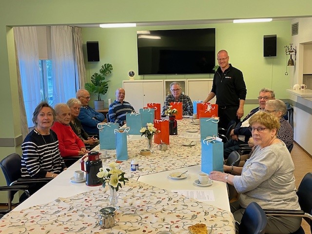 Vrijwilligers lachend op de foto in een ontmoetingsruimte