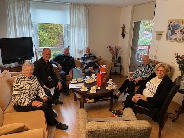 Vrijwilligers lachend op de foto in een woonkamer